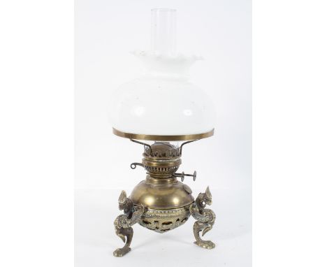 A Victorian brass oil lamp, the reservoir on three griffin legs, with a white glass shade, 44cm high