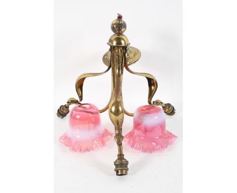 An Arts and Crafts style brass three light ceiling light, in the manner of Benson, with two glass shades, shading from pink t