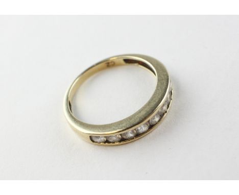 A yellow metal half hoop ring set with nine round cubic zirconias. Hallmarked 9ct gold, Birmingham. Size L ½ 2.0 grams