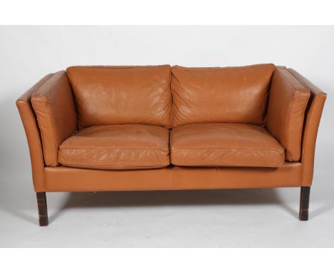 A Stouby late 20th Century tan leather upholstered two seat sofa, Danish, with slightly flaring back and arms, loose cushions