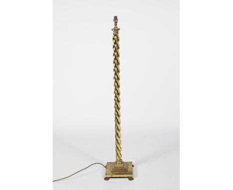 A polished brass standard lamp, the twisting column on a stepped square base and lion paw foot, 127cm high