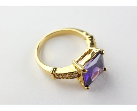 A yellow metal dress ring set with purple and white stones. Tested as gold plated. Size O 6.0 grams