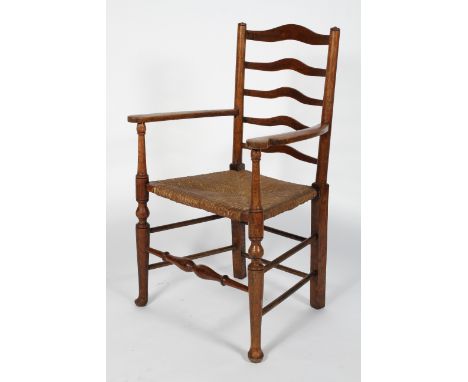 An oak and elm Arts and Crafts style arm chair, the wavy ladder back above scrolled arms, rush seat and baluster turned stret