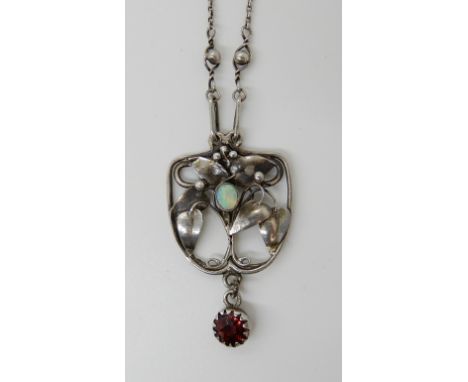 AN ART NOUVEAU WHITE METAL OPAL AND GARNET SET PENDANT the opal nestling among leaves and berries. Length of pendant 3.6cm, l