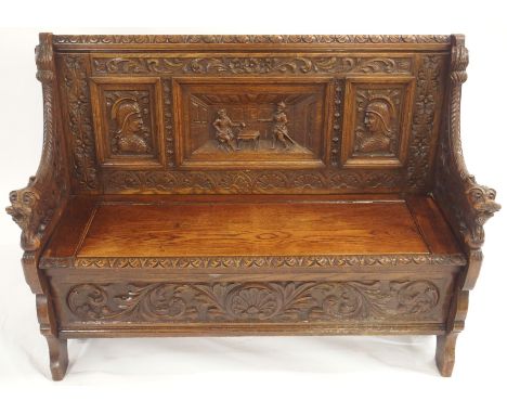 AN OAK HALL BENCH with three carved back panels, lidded seat and bearded lion arms and a floral carved front panel with an as