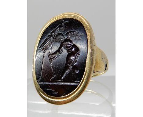 A CLASSICAL THEMED INTAGLIO OF CUPID AND A GRASSHOPPER carved in dark banded carnelian, the reverse unsigned, mounted in a ye