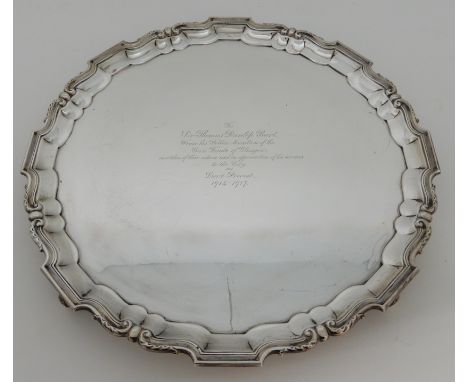 A LARGE SILVER PRESENTATION SALVER by R &amp; W Sorley, Glasgow 1915, of circular form with raised scalloped rim on four scro