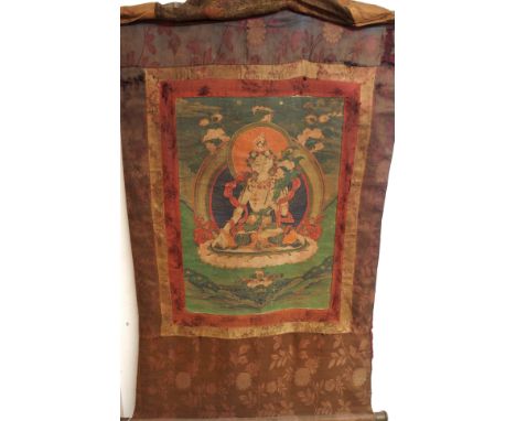 A TIBETAN THANGKA with female Buddha seated above the Earth and beneath the heavens, watercolour on paper within a silk surro