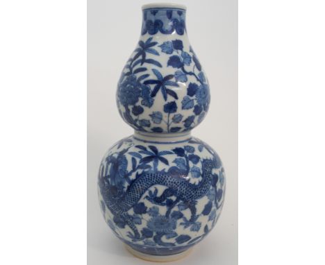 A CHINESE DOUBLE GOURD BLUE AND WHITE VASE painted with a pair of confronting dragons, amongst chrysanthemum, peonies and scr