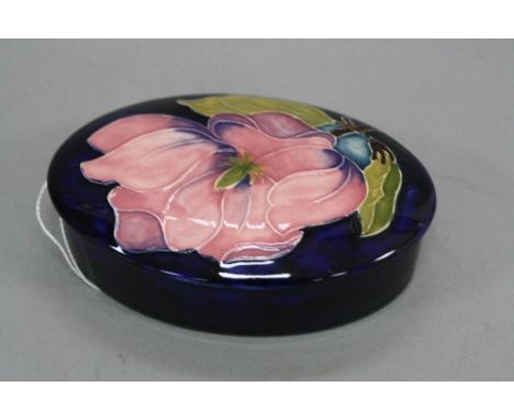 A MOORCROFT POTTERY OVAL COVERED TRINKET POT, Magnolia pattern on blue ground, impressed to base and labels to base and lid, 