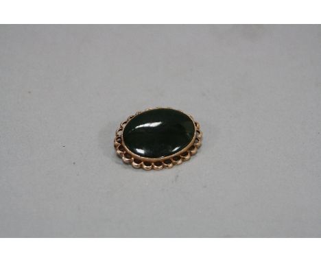 A MID TO LATE 20TH CENTURY NEPHRITE JADE BROOCH, oval cabochon measuring approximately 24mm x 18mm, miligraine set within a s