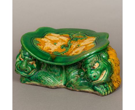 A Chinese Liao Dynasty pottery pillowOf typical form, decorated with deer, supported on a pair of temple lions.  29 cm wide. 