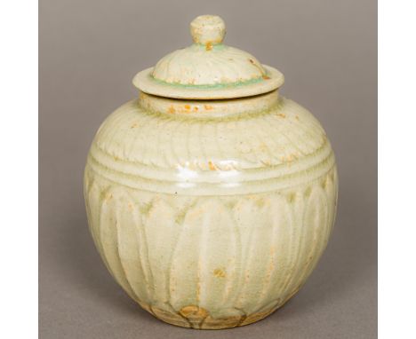 A Chinese Song Dynasty pottery pot and coverWith lapette carved decoration and all over celadon glaze.  13 cm high.Provenance