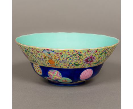 A Chinese porcelain bowlDecorated with various roundels on a blue ground below a lotus strapwork border, red painted six char