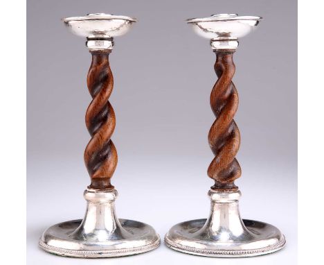 A PAIR OF GEORGE V SILVER AND OAK CANDLESTICKS, by Albert Edward Jones, Birmingham 1919, each with dished top and base with a