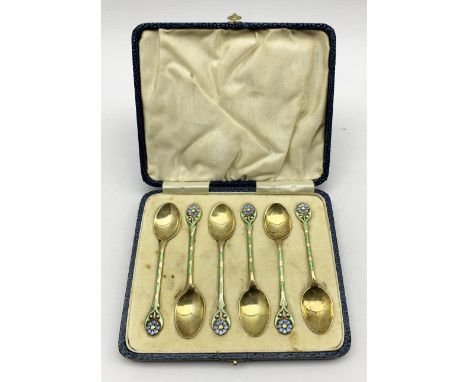 Set of six silver gilt coffee spoons, the finials decorated with a coloured enamel flower head, the stems with green panels a