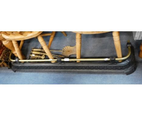 A VICTORIAN CAST IRON FENDER with a brass rail and a set of brass fireplace tools
