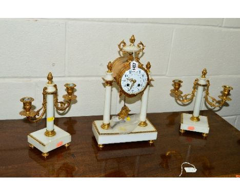 A LATE 19TH CENTURY WHITE MARBLE AND GILT METAL CLOCK GARNITURE, the clock with urn finial and bow above a circular enamel di