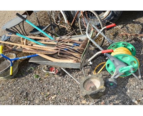 A WHEELBARROW, a quantity of garden tools, a hose reel and a large stone mortar