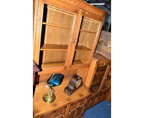 AN ERCOL ASH GLAZED TWO DOOR BOOKCASE, approximate size width 98cm x depth 30cm x height 27cm, together with an Ercol wall un