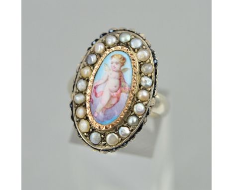 A VINTAGE WHITE METAL RING WITH A HAND PAINTED PORTRAIT OF A CHERUB, enclosed within a border of split pearls, ring size O1/2