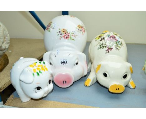 THREE CERAMIC STYLISED PIG MONEYBOX FIGURES, decorated with flowers to the bodies, the largest approximately 25cm tall