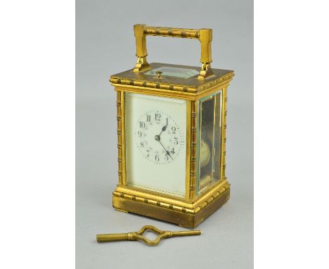 AN EARLY 20TH CENTURY GILT BRASS CARRIAGE CLOCK, the handle, four columns, pediment and foot cast with bobbin turned decorati
