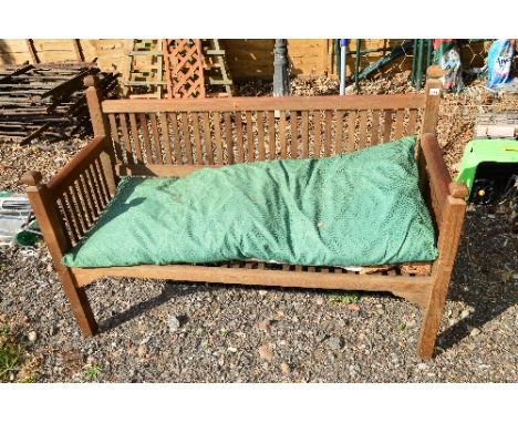 A HARDWOOD SLATTED GARDEN BENCH, approximate length 134cm, with a long soft cushion for seating