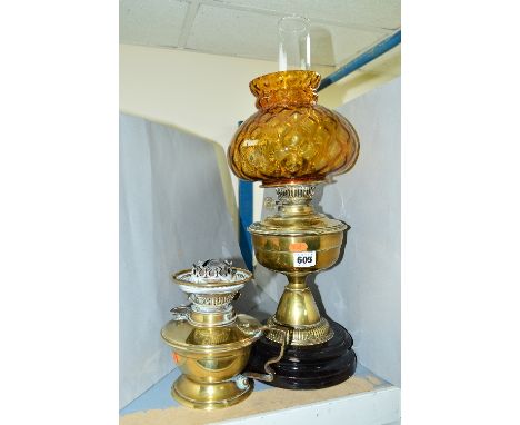 A VICTORIAN STYLE BRASS OIL LAMP, on a black painted stoneware base, the glass shade is of a textured amber glass, height exc