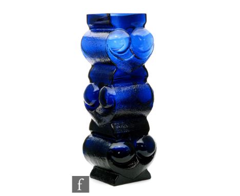 Lars Hellsten - Skruf - A post war glass owl vase in blue, of three tiers with alternating relief moulded stylised faces with