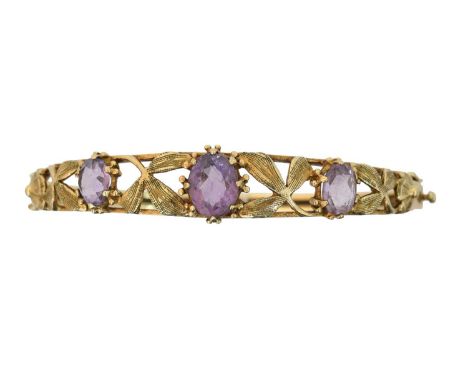 A 9ct gold amethyst hinged bangle, A 9ct gold amethyst hinged bangle, the oval shape amethyst line within an openwork foliate
