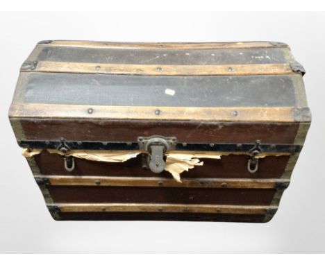 An early 20th century wooden bound dome top trunk containing linen.