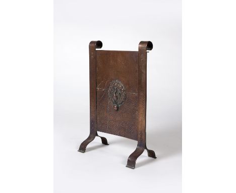 An Arts & Crafts copper firescreen with embossed peacock to centre on shaped feet 65.5cm high.