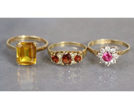 A 9ct. gold ring set small ruby within a border of white sapphires, size: N, (1.9gm); another set three graduated topaz with 