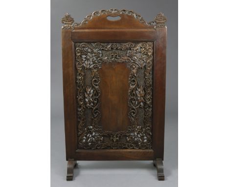 An Anglo-Indian hardwood firescreen, profusely carved &amp; pierced with scrolling foliage around a central cartouche; 22¼” w
