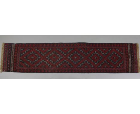 An Afghan runner of madder &amp; deep blue ground, with central row of five lozenges within multiple geometric borders; 8’8” 