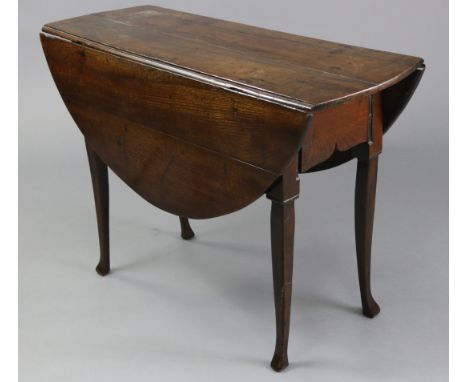 An 18th century joined oak gate-leg oval dining table, with drop leaves, shaped apron to each end, &amp; on four slender squa
