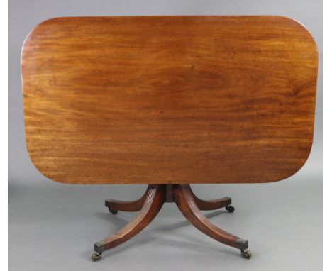A regency mahogany breakfast table, the rectangular one-piece tilt-top with plain edge, on ring-turned centre column &amp; fo