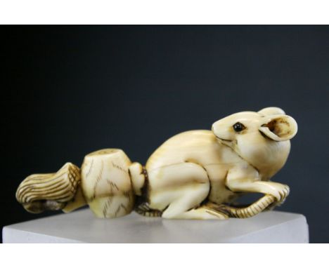 A 19th Century ivory netsuke of a rat, signed. Seated looking backards with it's tail running through a barrel ending in a ta