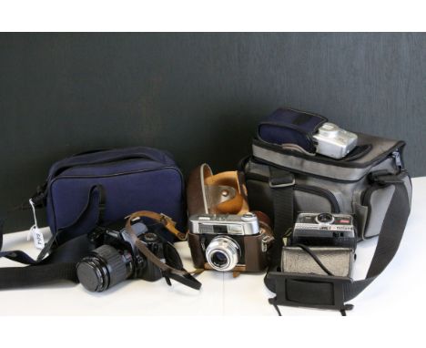 A cased Canon eos 1000f  camera with accessories, a cased voightlander and two other cameras.