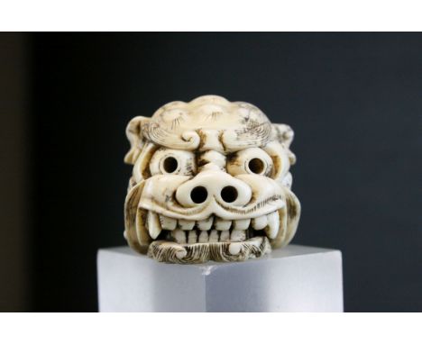 A IVORY NETSUKE OF A SHISHI HEAD IN THE MANNER OF TOMOTADA, Signed, well carved with a hinged opening jaw revealing tongue an