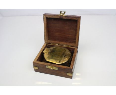 A brass compass contained within a wooden case with brass anchor.