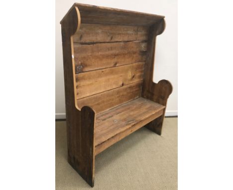 A Victorian pine tavern type settle with canopy bearing carved inscription "Wade" over a panelled back flanked by winged plan