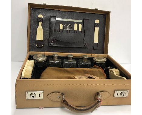 An early 20th Century travelling vanity case with fitted interior containing ivorine mounted brushes, manicure tools etc and 