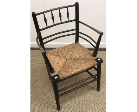 A circa 1900 ebonised beech and ash framed Sussex chair after the original design by William Morris with rush seat on turned 