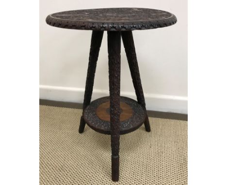 A Burmese carved teak occasional table, the circular top on three splayed supports united by an undertier, bearing enamel tag