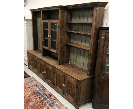 A modern oak dresser in the 18th Century style, the breakfront upper section with moulded cornice over a shelf and two glazed