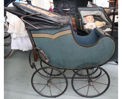 A Victorian large dolls pushchair/pram with painted wooden body, rexine hood, brown button back rexine interior. Four even si