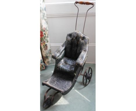 An early 19th century dolls pushchair. With button leatherette seat, foot rest, three metal spoke wheels and a turned wooden 