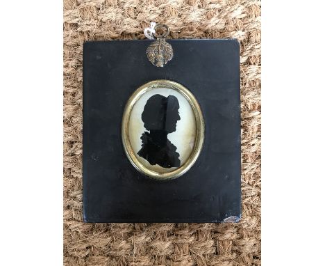 A Georgian silhouette portrait of a lady reverse painted on glass with lace bonnet and ruffle collar, in black lacquered fram